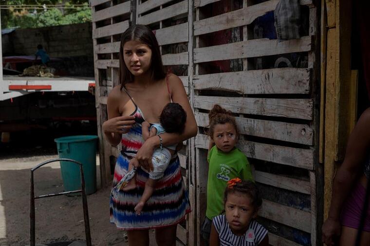 Una mujer amamantaba a su hijo frente a su vivienda improvisada en un terreno ocupado en Caracas, Venezuela.