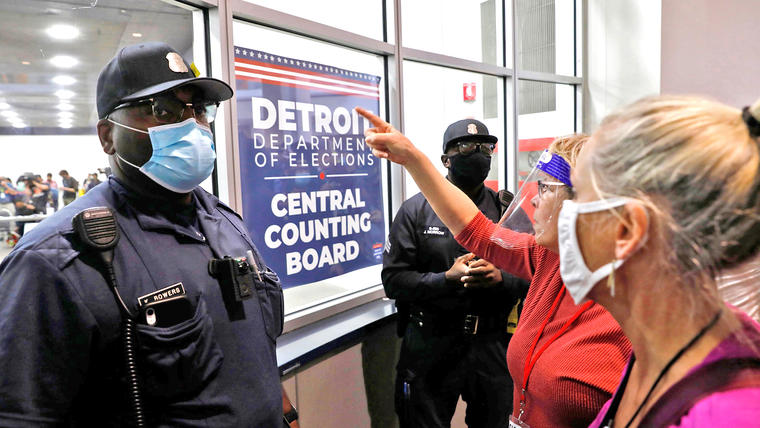 Dos oficiales de policía se paran frente a partidarios de Trump que corean consignas fuera de la sala donde se cuentan las papeletas de voto en ausencia para las elecciones, el 4 de noviembre de 2020 en Detroit, Michigan. 