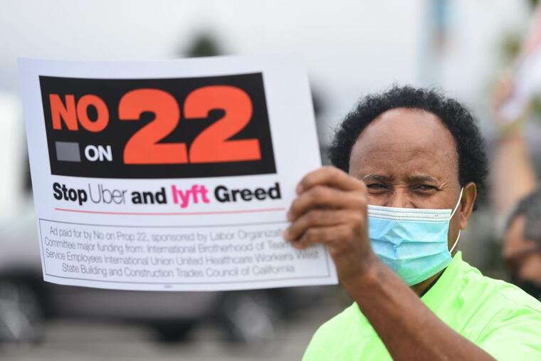 Un conductor sostiene un letrero en contra de la Proposición 22
