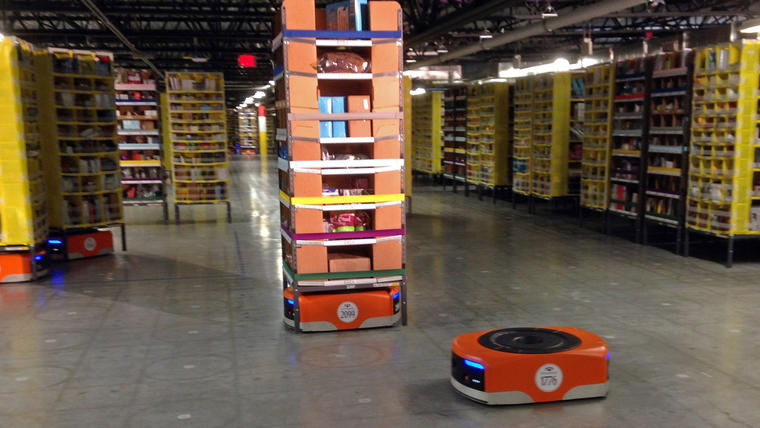 Imagen de un robot Kiva, al frente, antes de transitar entre estanterías de mercancía en el nuevo centro de distribución de Amazon en Tracy, California, el domingo 30 de noviembre de 2014