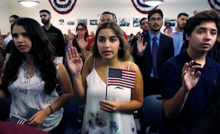Ericka Ames, centro, de Nicaragua, recita el Juramento de Lealtad en  una ceremonia de naturalización en agosto de 2018, en Miami.