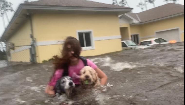 Julia Aylen, una residente de Freepor Bahamas, vadea el agua profunda mientras carga a sus mascotas para sacarlas de su hogar inundado