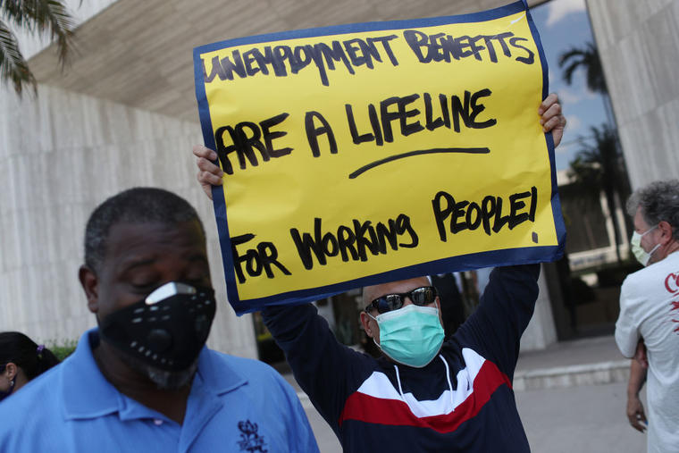 "Los benedifios del desempleo son vitales para los trabajadores", reza la pancarta de Carlos Ponce en una manifestación en Miami esta semana.