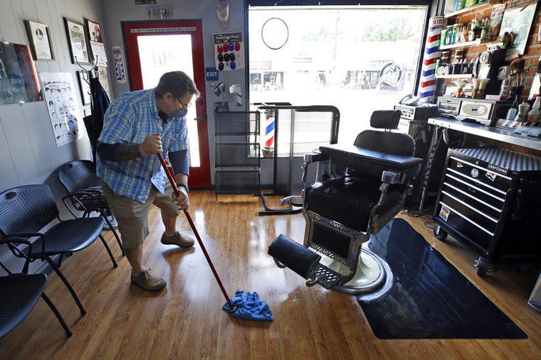 El dueño de una peluquería en Sacramento trapea el piso de su negocio 