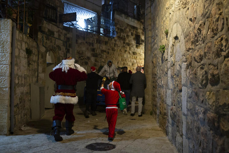 Un niño y un hombre vestidos de Santa Claus caminan por las calles del sector cristiano de Jerusalem