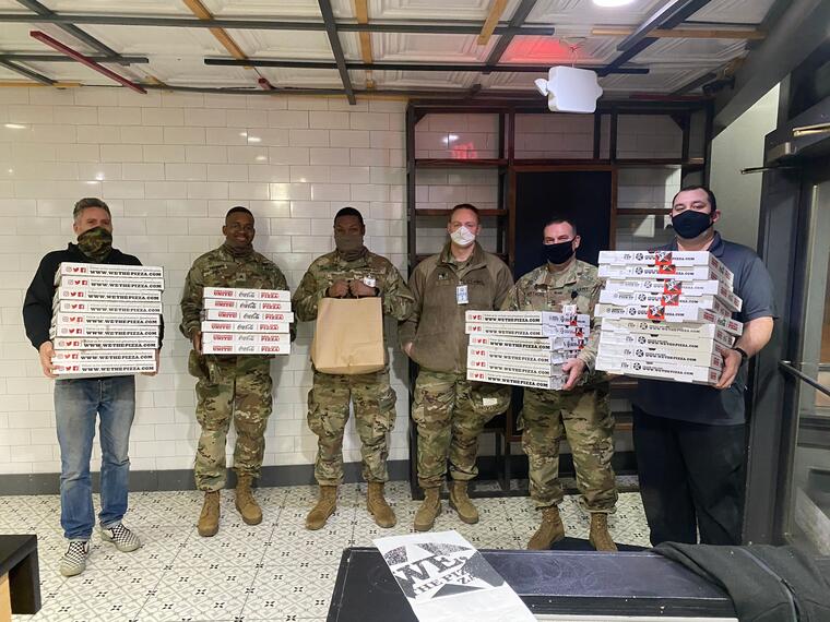 Miembros de la Guardia Nacional sostienen cajas de pizzas en un restaurante de Washington D.C.
