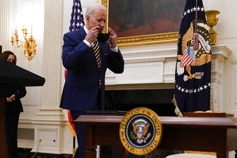 El presidente, Joe Biden, se coloca su mascarilla antes de firmar una serie de órdenes ejecutivas.