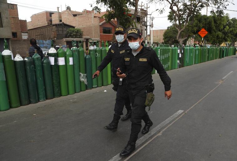 Policías con mascarillas vigilan el orden el lunes 25 de enero de 2021 afuera de un establecimiento en Callao, Perú
