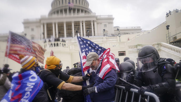 Un grupo de manifestantes intentan levantar la barrera policial e ingresar al Capitolio tras un incendiario discurso por parte del entonces presidente, Donald Trump. 