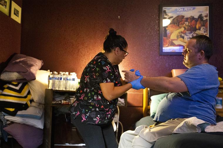 Irma Núñez, asistente de salud a domicilio, ayuda a su cliente Thomas Draa, que es tetrapléjico, a acostarse en su cama, el 14 de abril de 2021 en Las Vegas. 