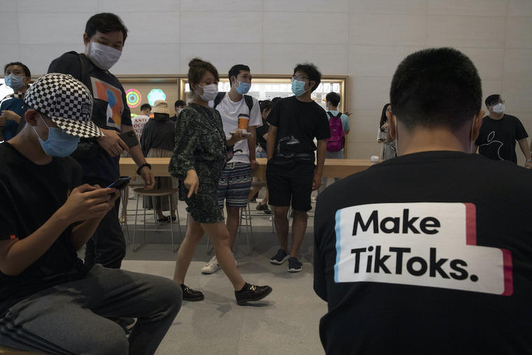 Jóvenes -uno de ellos con una camiseta promocional de TikTok- en una tienda de Apple en Pekín, China, 17 de julio del 2020. Alrededor del mundo, plataformas como TikTok han ganado popularidad entre niños y adolescentes. Imágen con fines ilustrativos. 