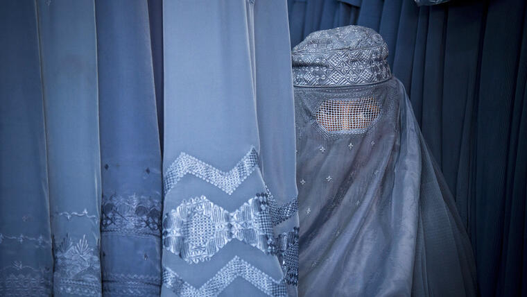 Una mujer afgana mira por la rendija de su burqa mientras espera para probarse una nueva burqa en una tienda en Kabul, Afganistán, el 11 de abril de 2013.