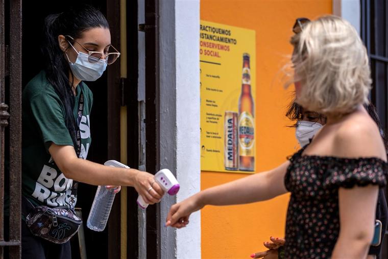 Una empleada de un restaurante en Viejo San Juan, Puerto Rico, chequea la temperatura de una clienta el 20 de julio de 2020. 
