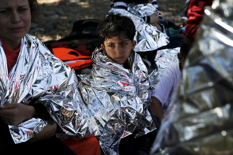 A Syrian refugee boy is wrapped with a thermal blanket after a dinghy carrying Syrian and Afghan refugees deflated some 100m away from the shores of the Greek island of Lesbos