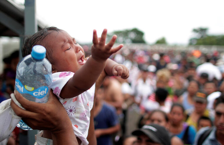 Un bebé llora mientras que los adultos que lo acompañan esperan en la ciudad de HIdalgo, en México, para pedir asilo. 