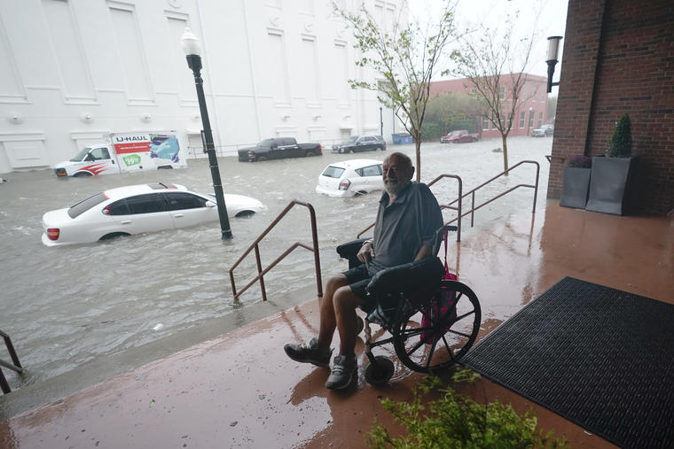 Un hombre en silla de ruedas observa desde una zona alta una calle inundada 