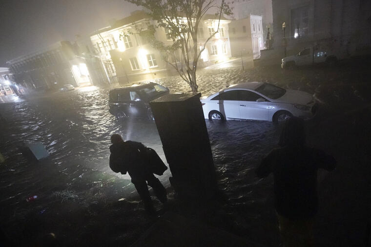 Una persona usa una linterna mientras camina por calles inundadas