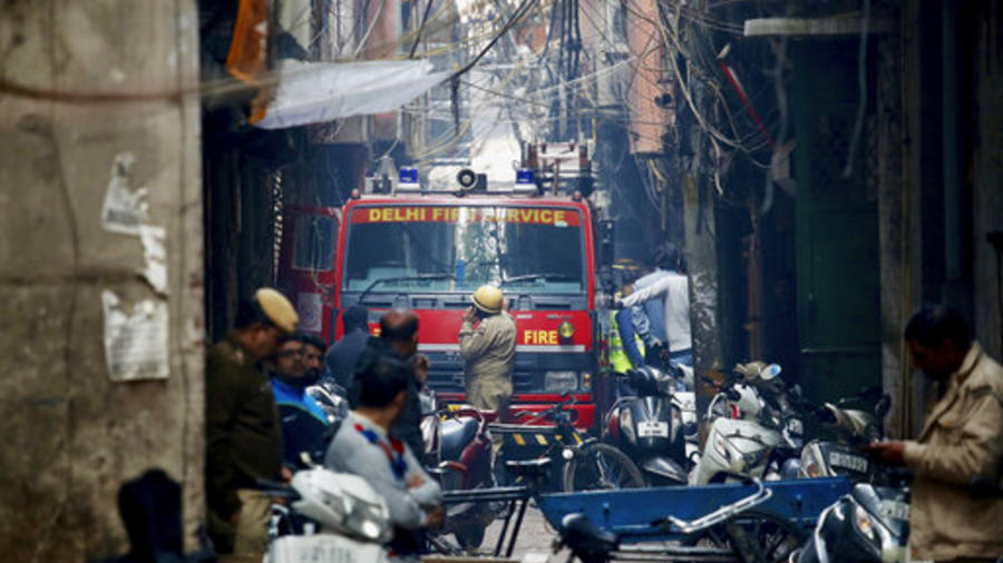 Un camión de bomberos se encuentra junto al lugar de un incendio en un callejón, enredado en cables eléctricos y demasiado estrecho para que los vehículos puedan acceder, en Nueva Delhi, India, el domingo 8 de diciembre de 2019.