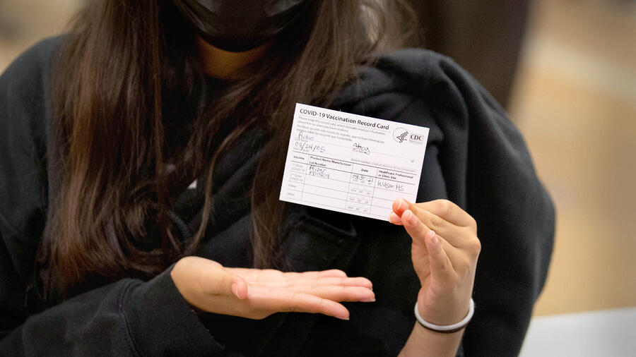 Una chica muestra su tarjeta de prueba de vacunación contra el COVID-19. 
