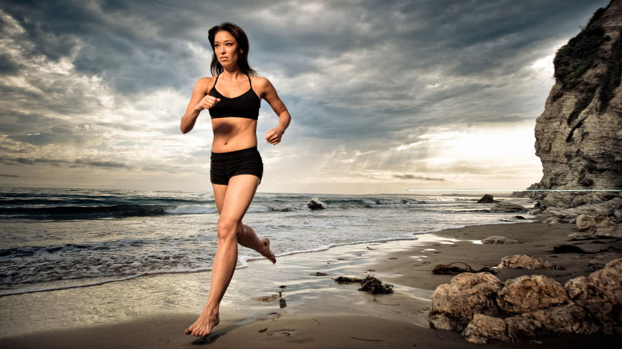Mujer joven corriendo descalza en la playa