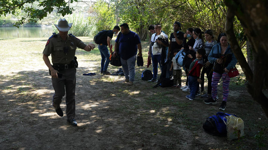 Agentes del Departamento de Seguridad Pública de Texas atienden a un grupo de migrantes que cruzaron la frontera