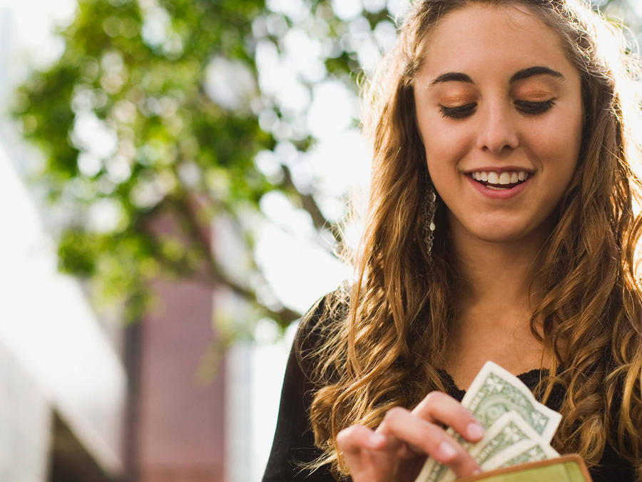 Chica adolescente revisa billetes y sonríe