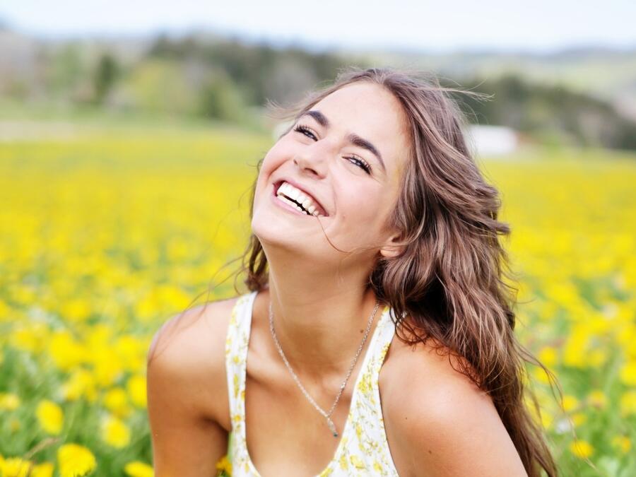 Mujer sonriendo en un prado con flores amarillas