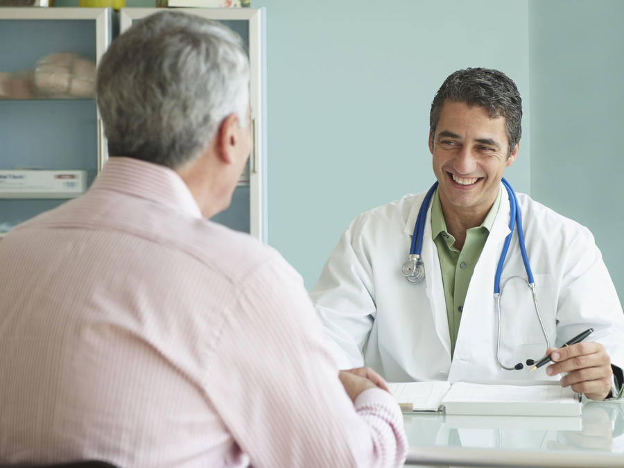 Médico sonriendo mientras habla con un paciente