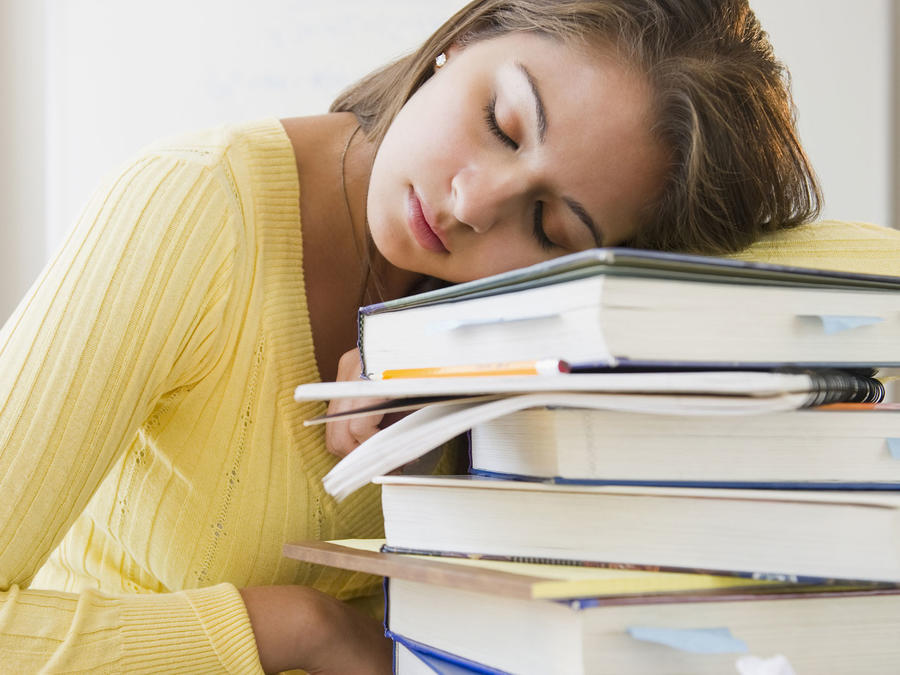 Mujer joven dormida en su banco sobre una pila de libros