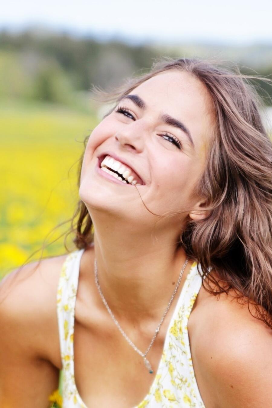 Mujer sonriendo en un prado con flores amarillas