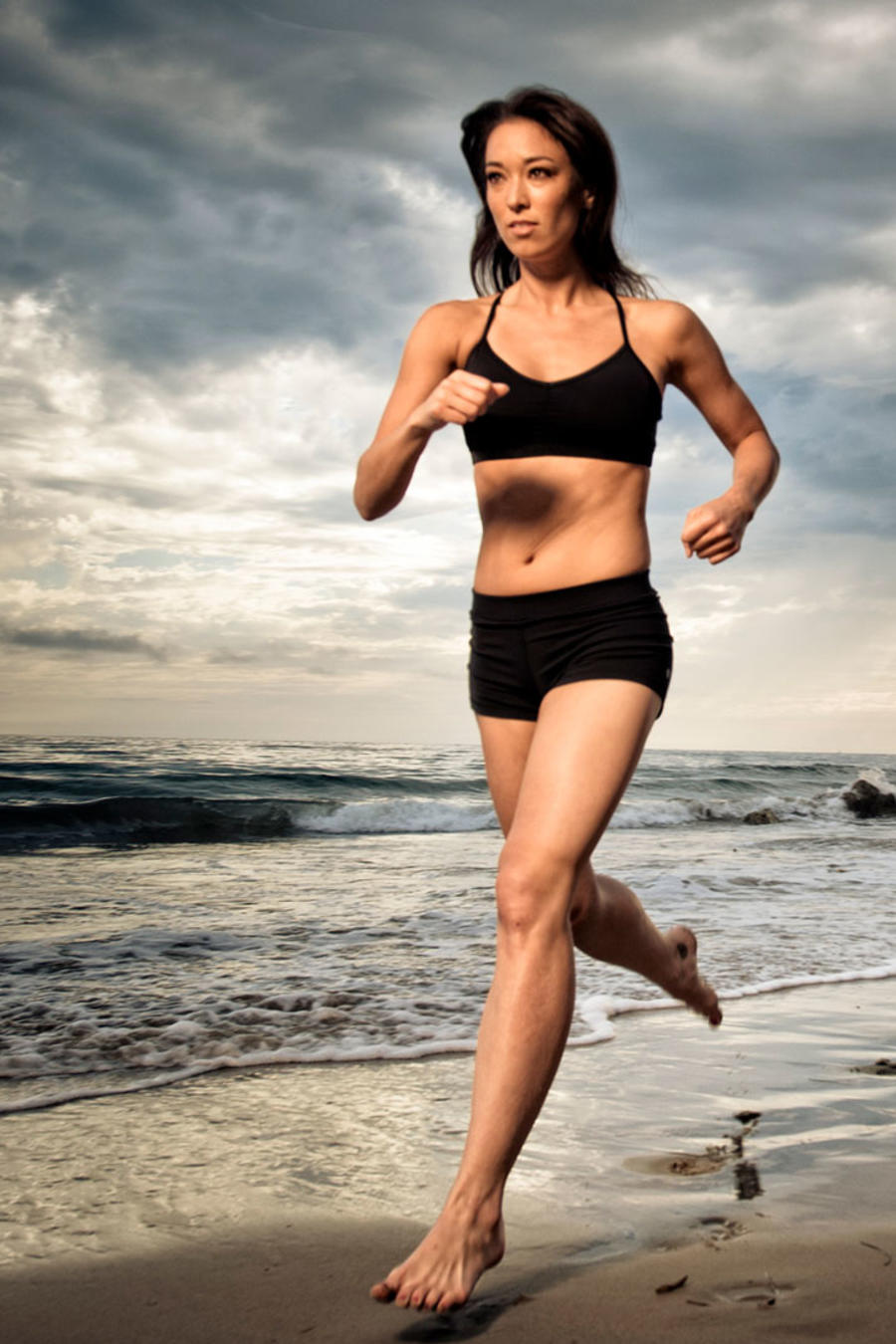 Mujer joven corriendo descalza en la playa