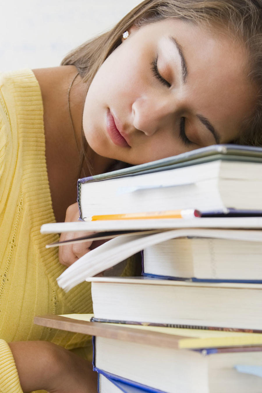 Mujer joven dormida en su banco sobre una pila de libros