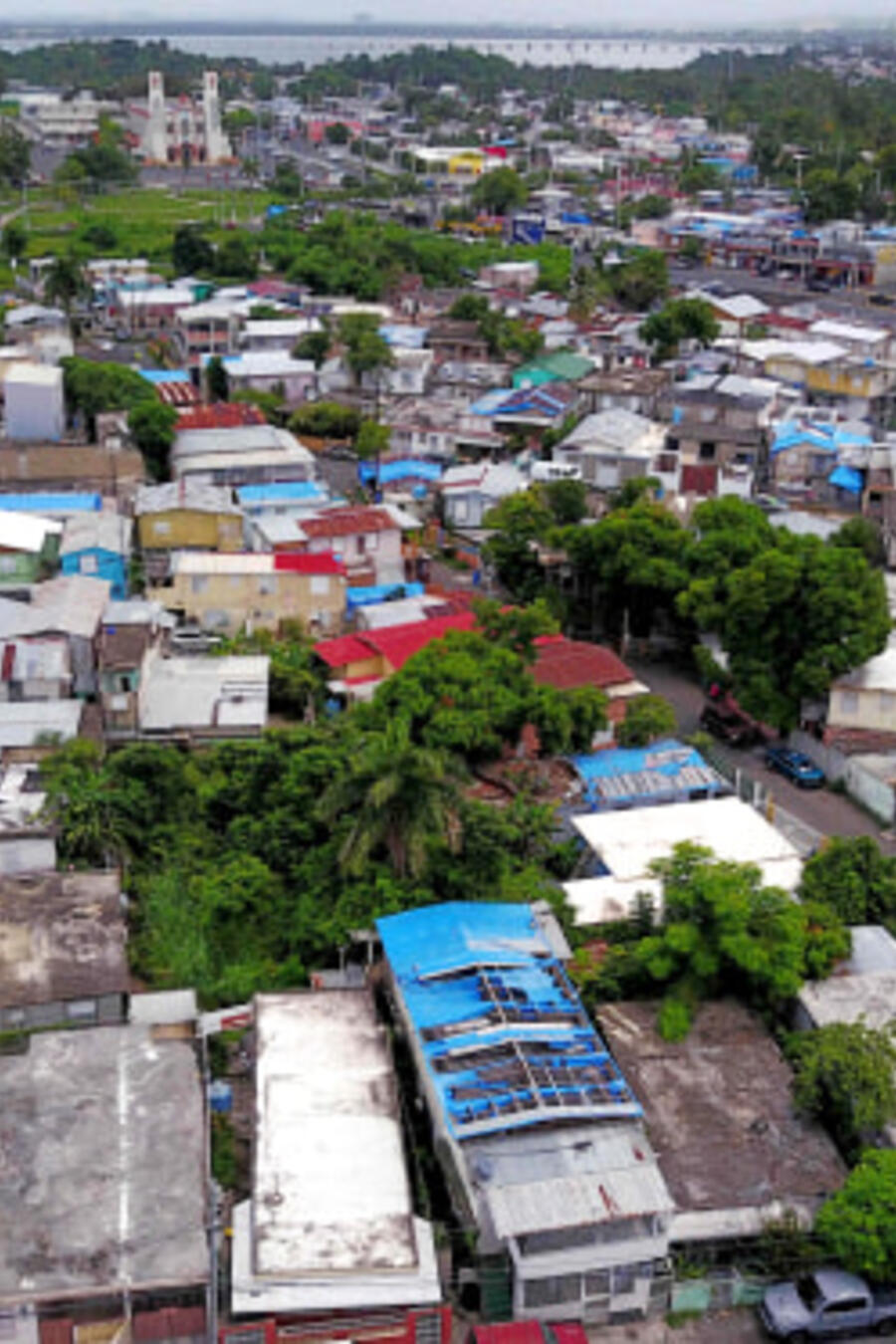 Lonas azules repartidas por FEMA cubren varios techos de viviendas dañadas en Puerto Rico dos años después del huracán María.