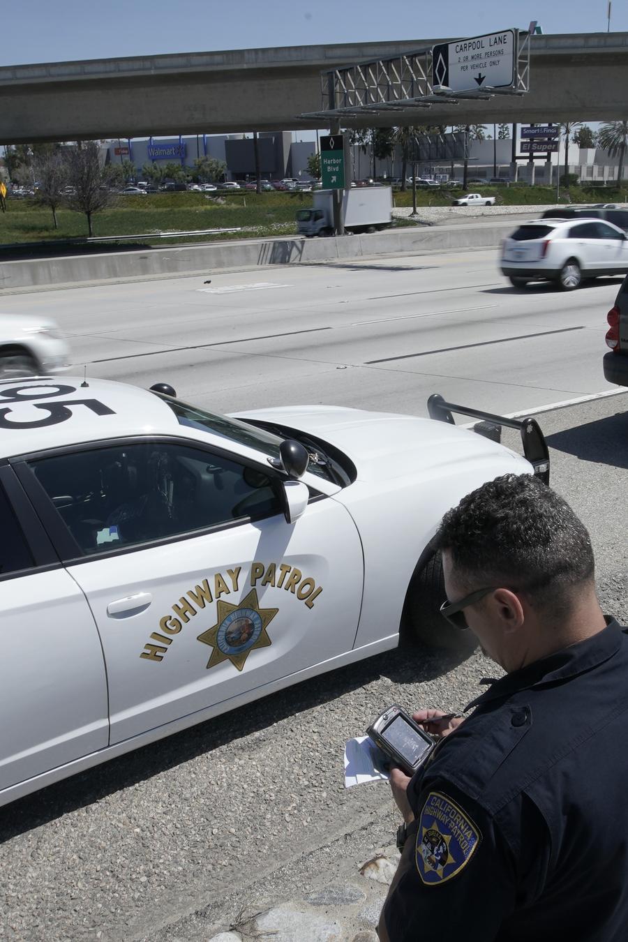 En esta imagen del 23 de abril de 2021, el oficial de la Patrulla de Caminos de California Troy Christensen revisa una licencia de conducir después de detener a un automovilista en la Interestatal 5 que conducía a exceso de velocidad en Anaheim, Californi