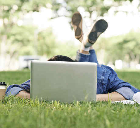 Estudiante con computadora en el pasto