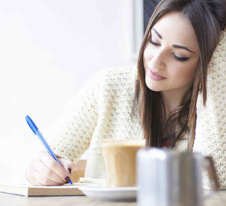 Mujer joven escribiendo y bebiendo café
